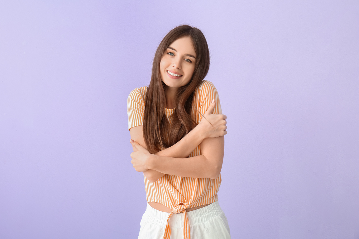 Young Woman Hugging Herself on Color Background